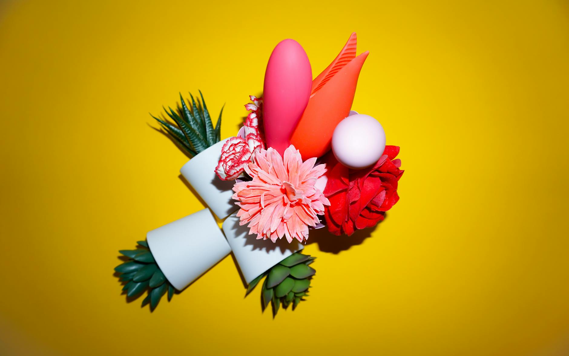 Hand reaching over a variety of colorful sex toys arranged on a table